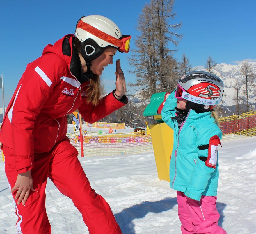 Skilehrerin mit Kind beim High-5