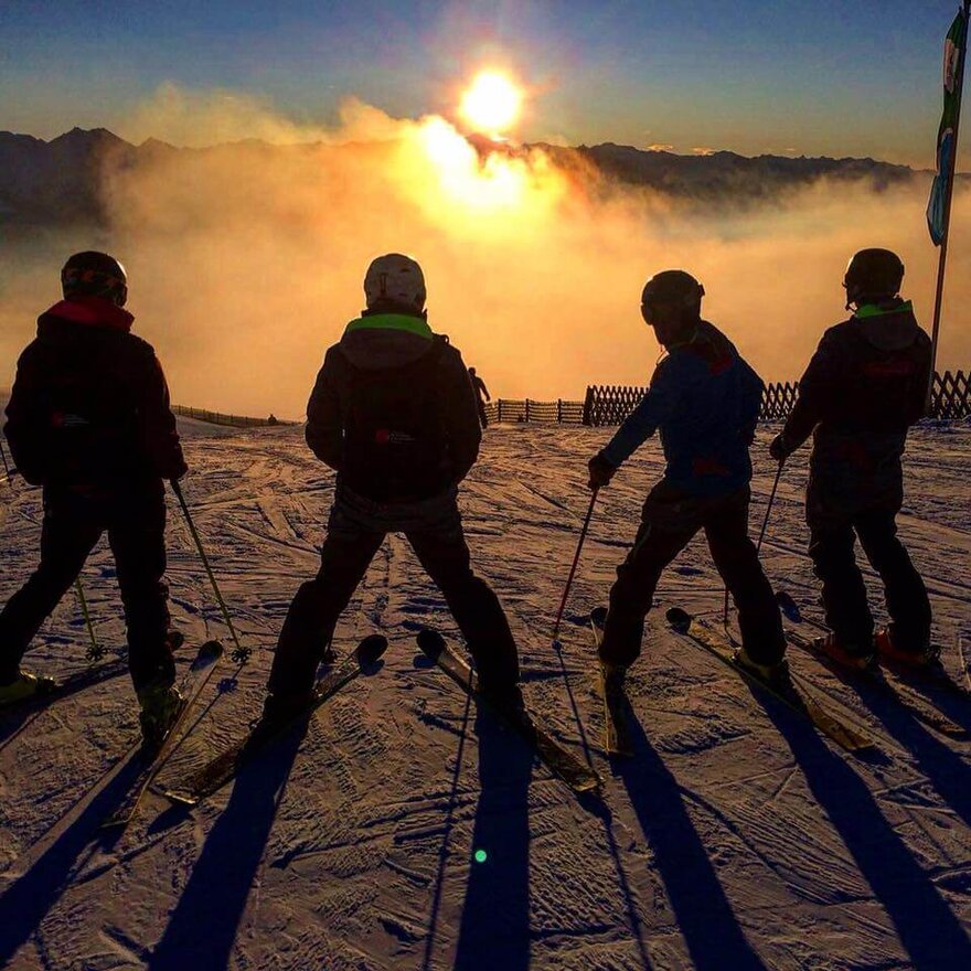 Gruppe von Skifahrern bestaunt den Sonnenuntergang am Berg